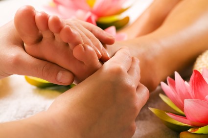 Handen masseren een voet, met lotusbloemen